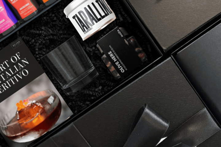 DLISH curated Italian corporate gift box featuring The Art of the Italian Aperitivo book, BRYPE bitters, Tarallini, and Olive Nere on dark background
