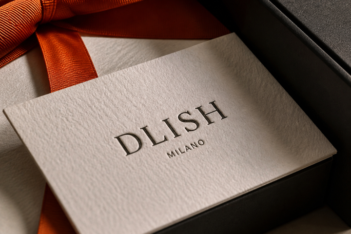DLISH Milano letterpress branded card on a dark gift box with orange satin ribbon, an example of audit-ready luxury corporate gifting documentation.