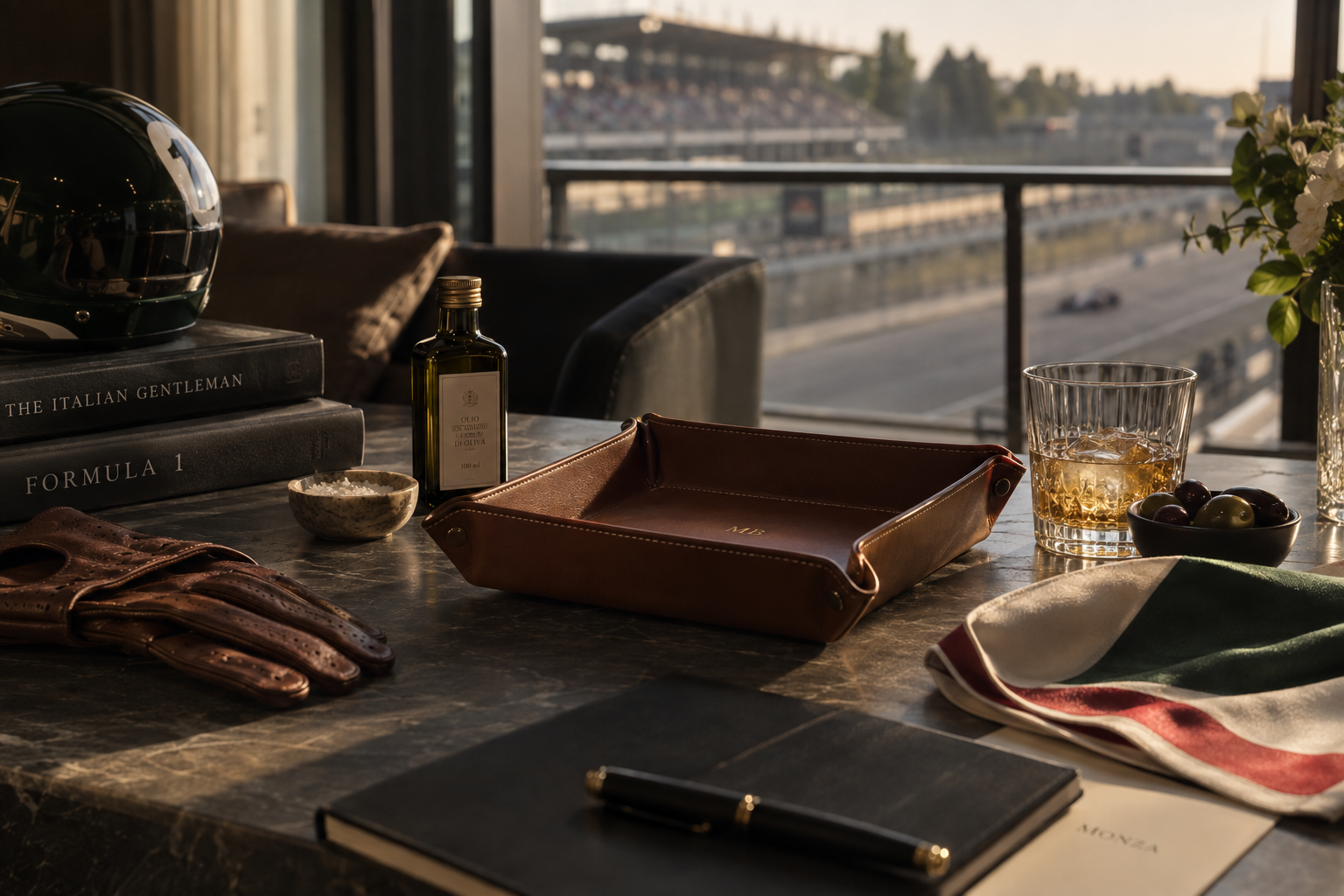 Monza executive gift concept by DLISH: Italian leather valet tray, estate olive oil, and a silk pocket square in vintage racing colors on a marble table overlooking the Monza circuit, a design proposal for a $150 Formula 1 gift