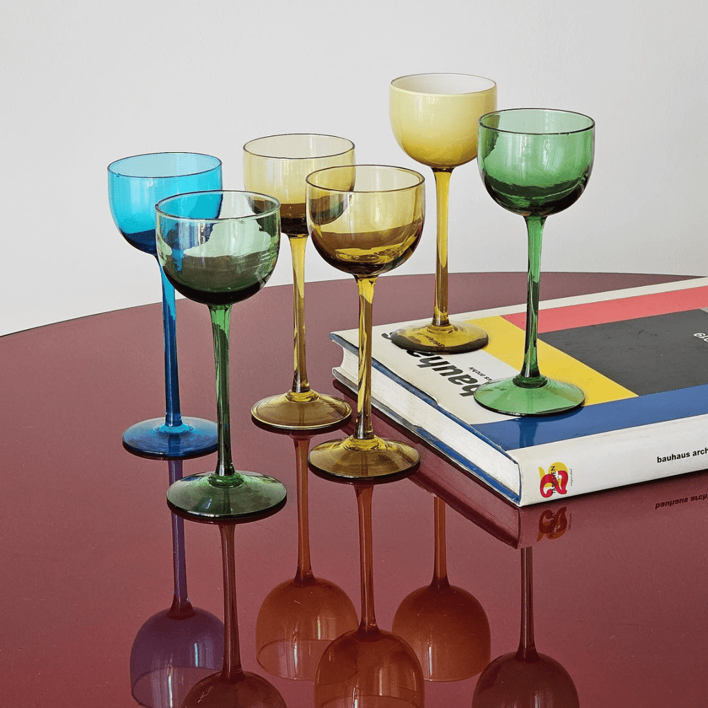 Set of 6 multicolor vintage Carlo Moretti Murano glasses for amaro, limoncello, or wine, displayed on red table with Bauhaus book