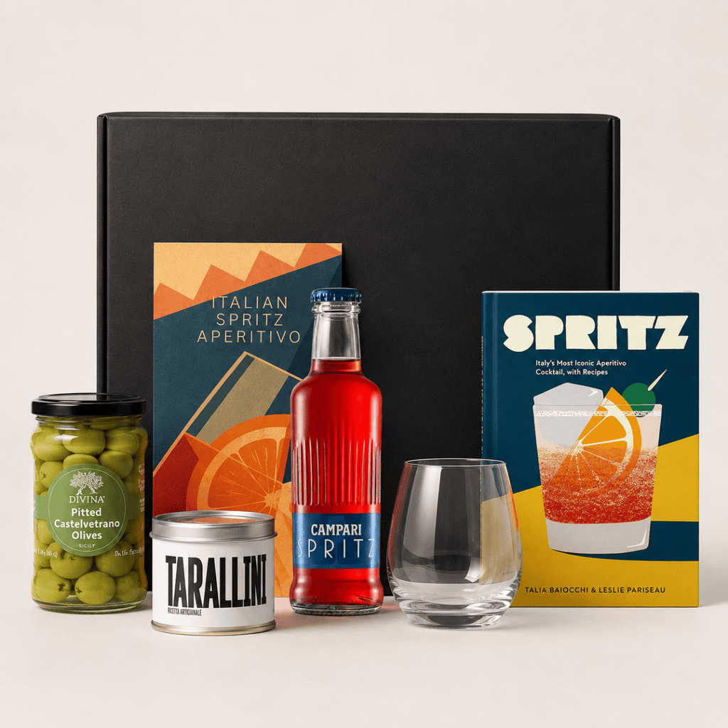 Italian Spritz Gift Box with Campari Spritz bottle, stemless wine glass, Divina Castelvetrano olives, artisan tarallini, aperitivo insert card, and Spritz recipe book displayed in front of matte black gift box